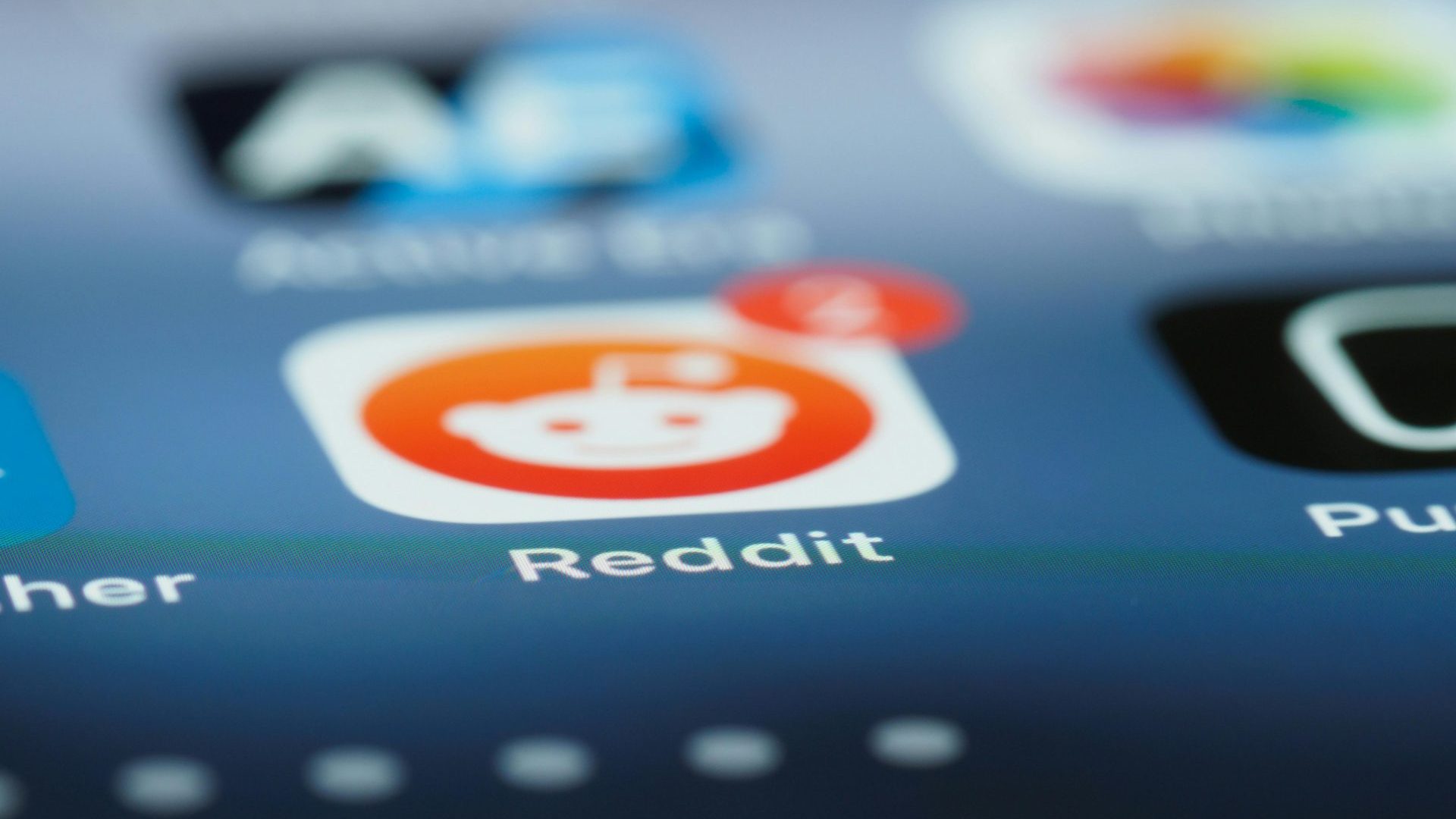 Close-up of the Reddit app icon on a smartphone screen, notification badge with 2 alerts, reflecting Smarter Media’s strategic expertise.